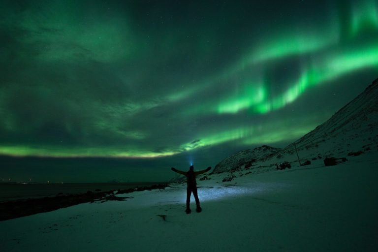 The Northern Lights coming through a thin layer of clouds at Lyngstuva point in the far north of Lyngen © Petr Pavlíček / Visit Lyngenfjord