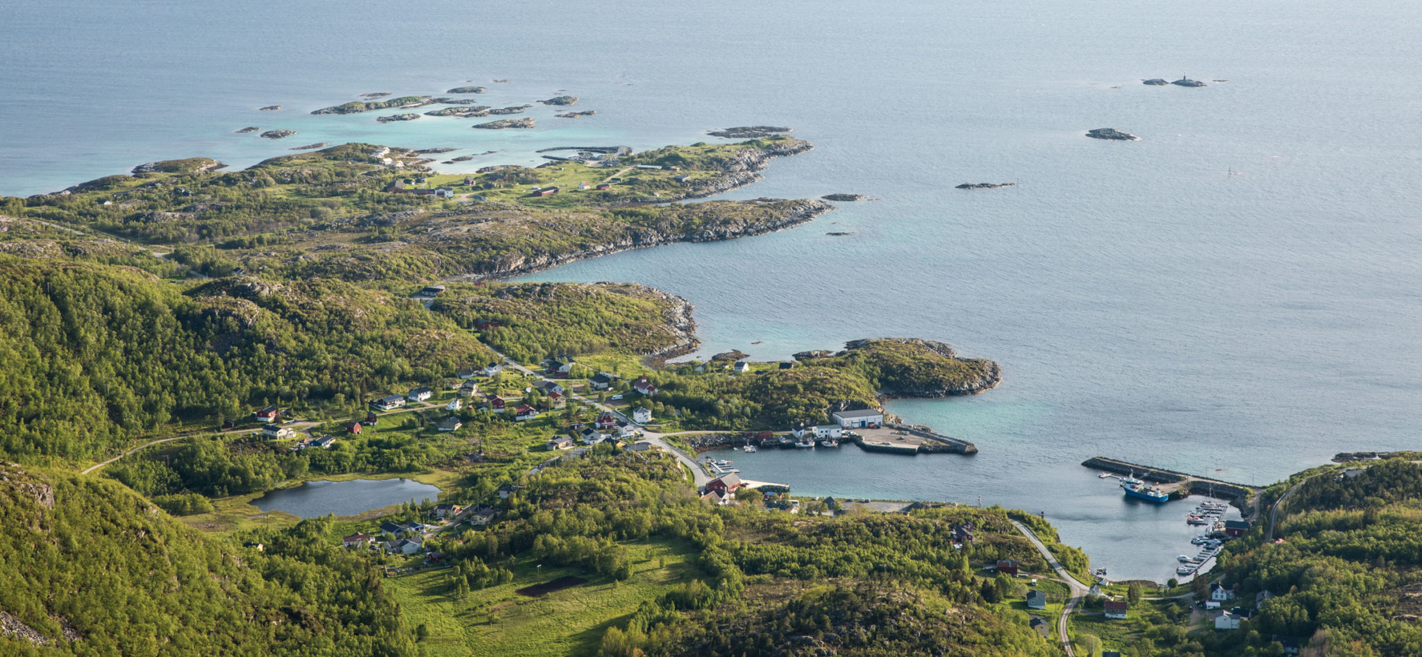View of Skrolsvik on Senja's south-western tip. The Halibut Museum is the red wharf in the harbour below the centre of the photo. The upper left area is the Skrolsvik Fort area. The fortress was established by the German occupying forces, and used by the Norwegian navy until 1991 © Dag Arild Larsen / Midt-Troms museum